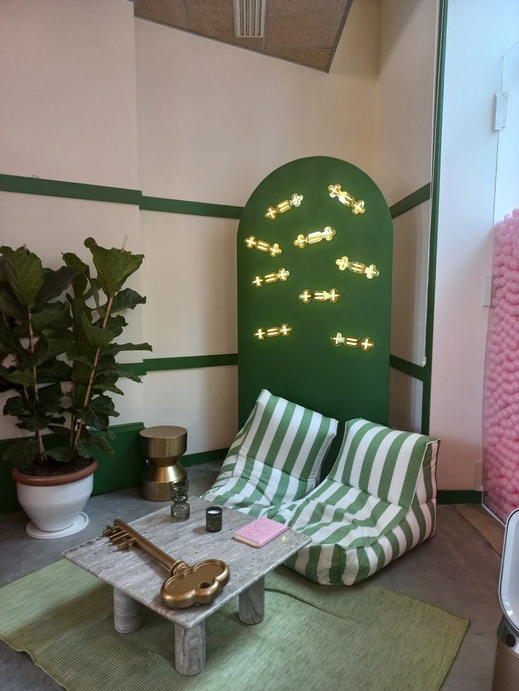 Coin lounge cosy à l’Hôtel Mahfouf, avec fauteuils rayés verts et table basse ornée d’une clé dorée.